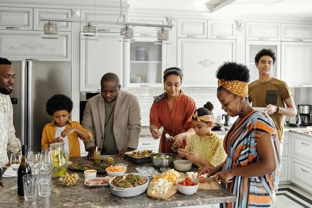 Manter ou não contato com a família do ex? Na imagem, uma família negra se reúne na cozinha para fazer comida.